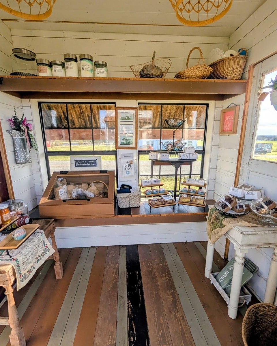 Inside the little white farmstand, with baked goods and handmade items arranged on shelves and tables